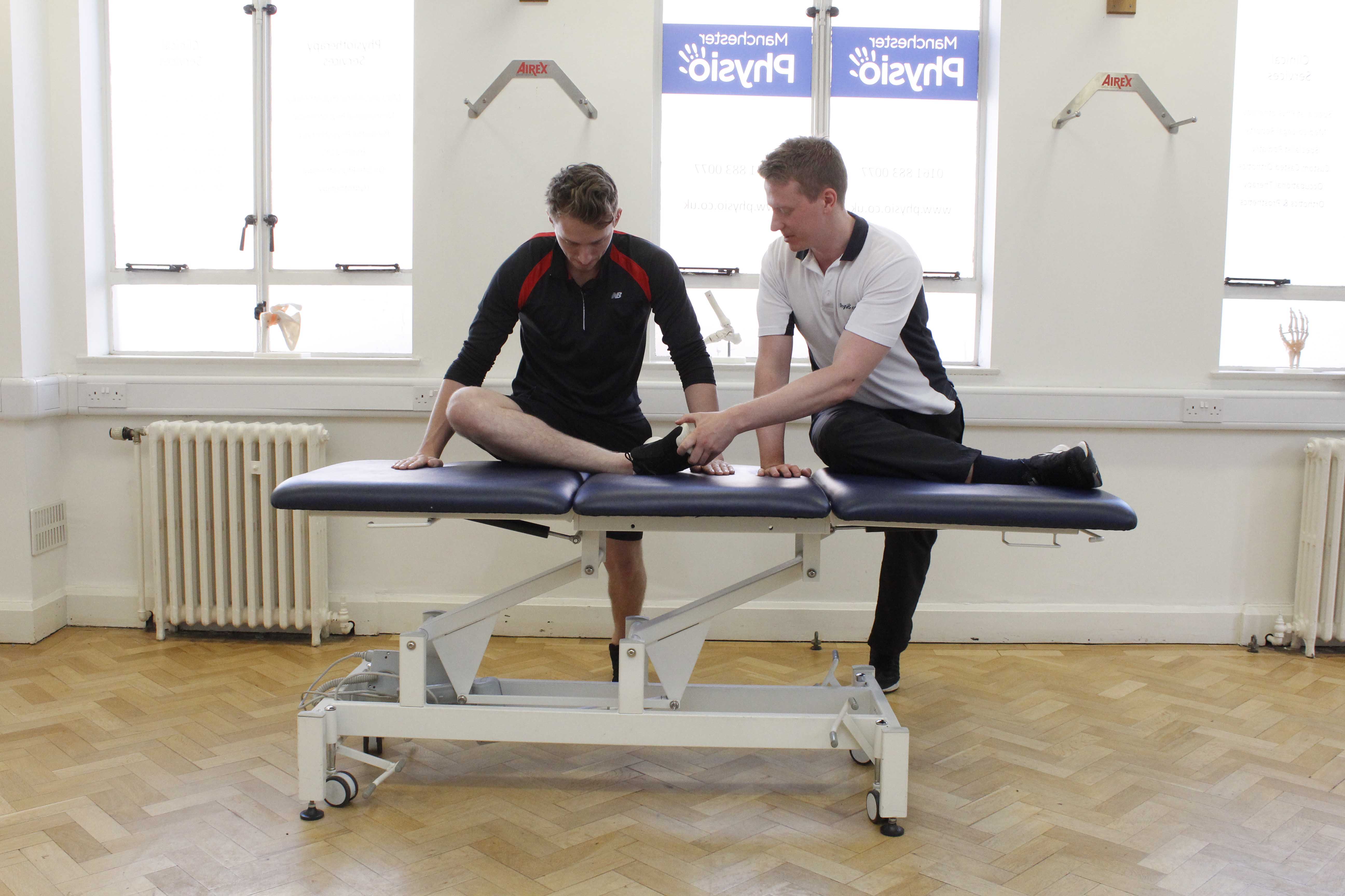 Specialist musculoskeletal Physiotherapist supervising hip and knee stretches for sports rehabilitation